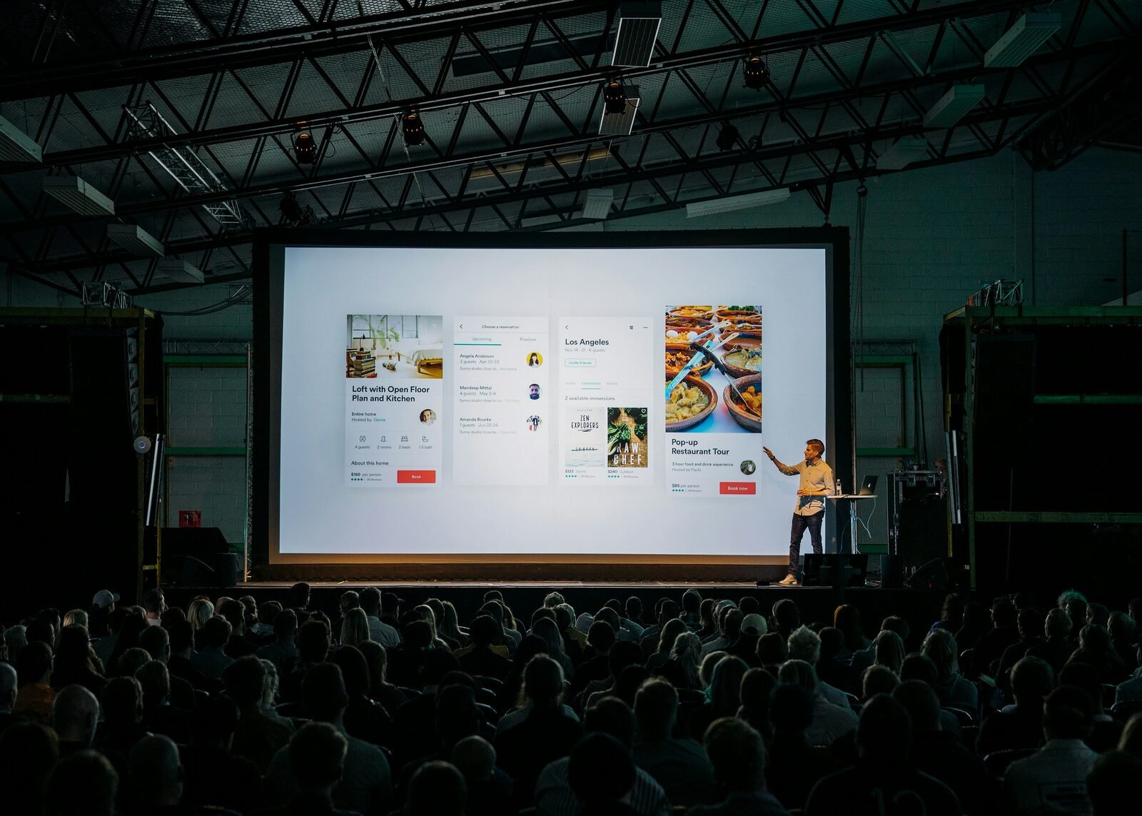 Speaker presenting to an audience in a dimly lit conference room.